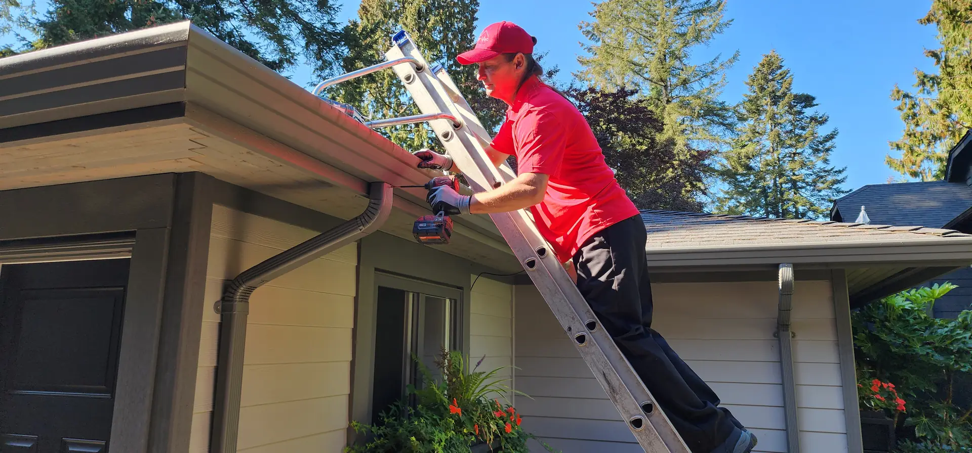 Contractor cleaning gutters from a ladder