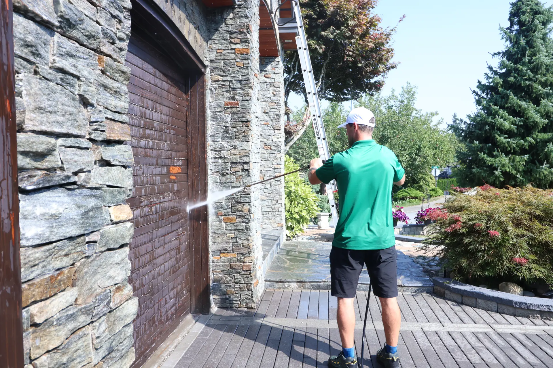 Contractor pressure washing a stone wall